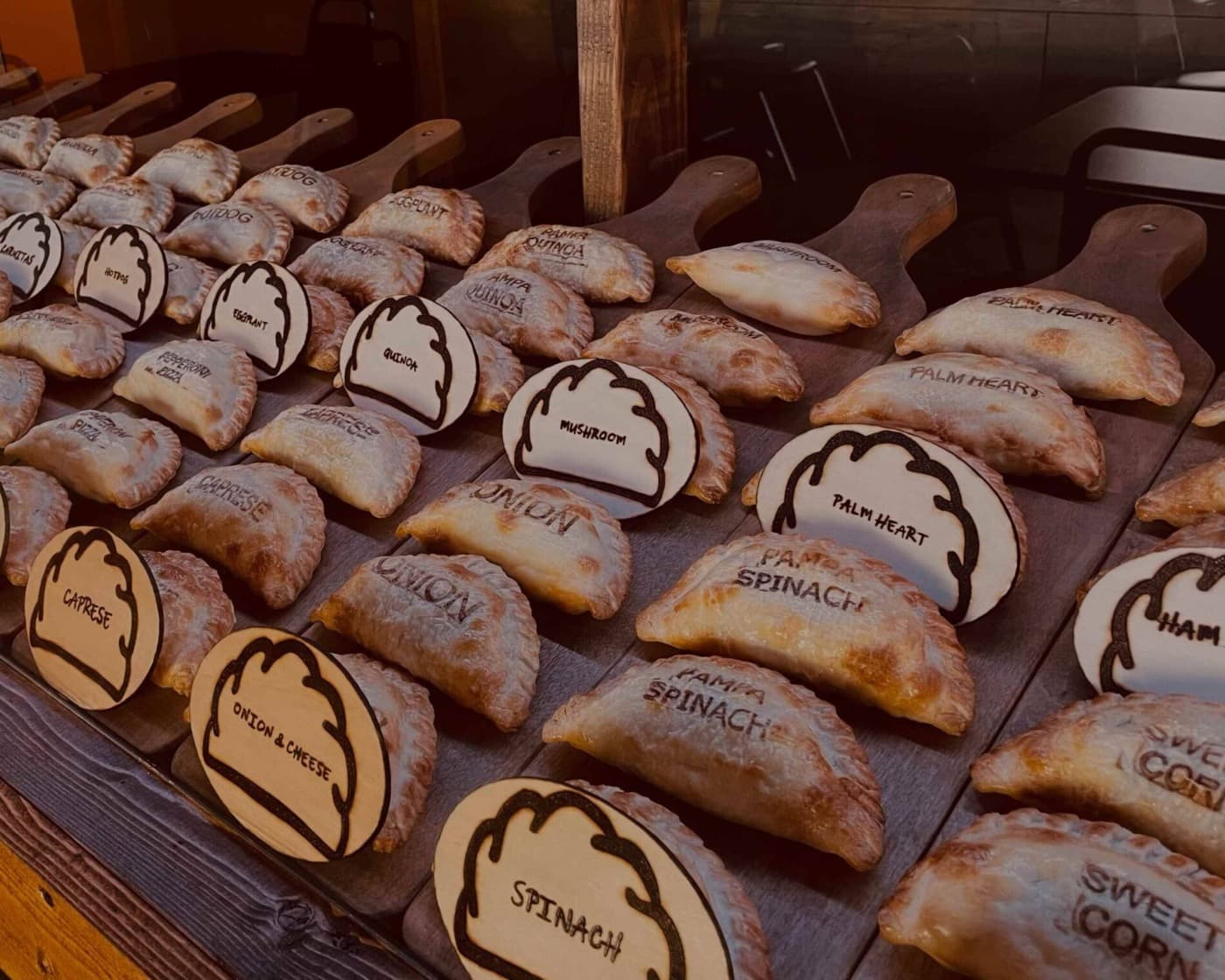 Board full of Pampa Empanadas with their flavors branded on the dough